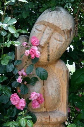 The Mantifang 1 Wooden garden statue surrounded by flowers, expressing care for nature in everyday Korean settings